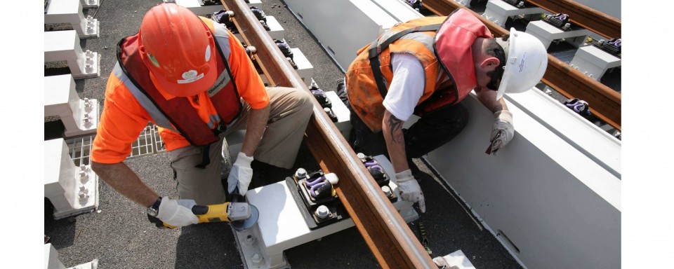 Contractors work to secure the rails to the deck
